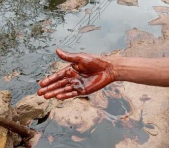 A resident scoops from the fresh oil spill in Bodo community, Rivers.