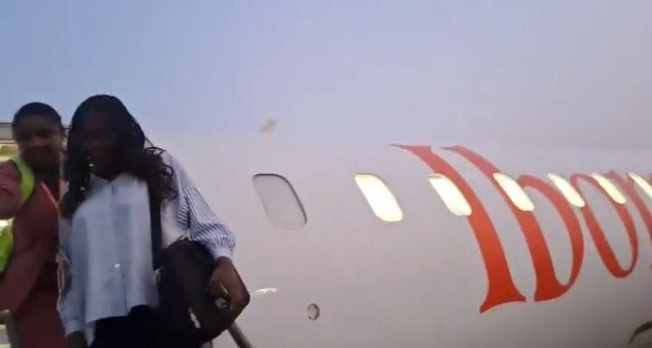 An airport official escorting the passenger out of the aircraft in Uyo